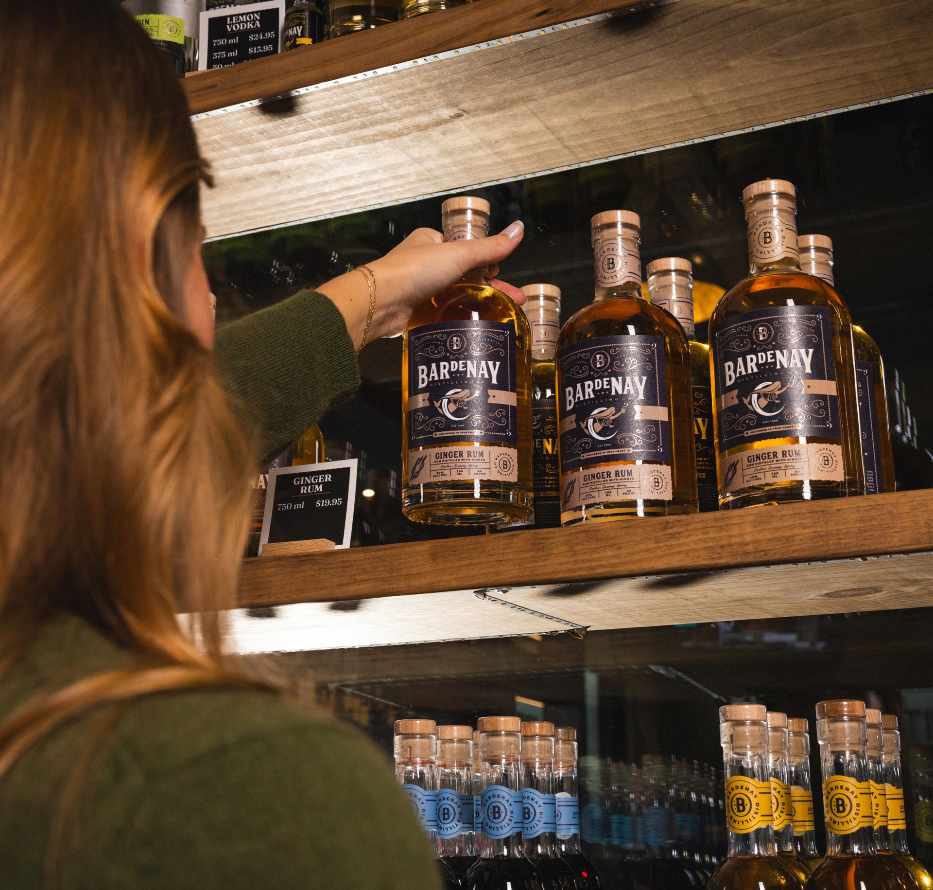 Woman grabbing a bottle of Bardenay Ginger Rum off of a shelf.